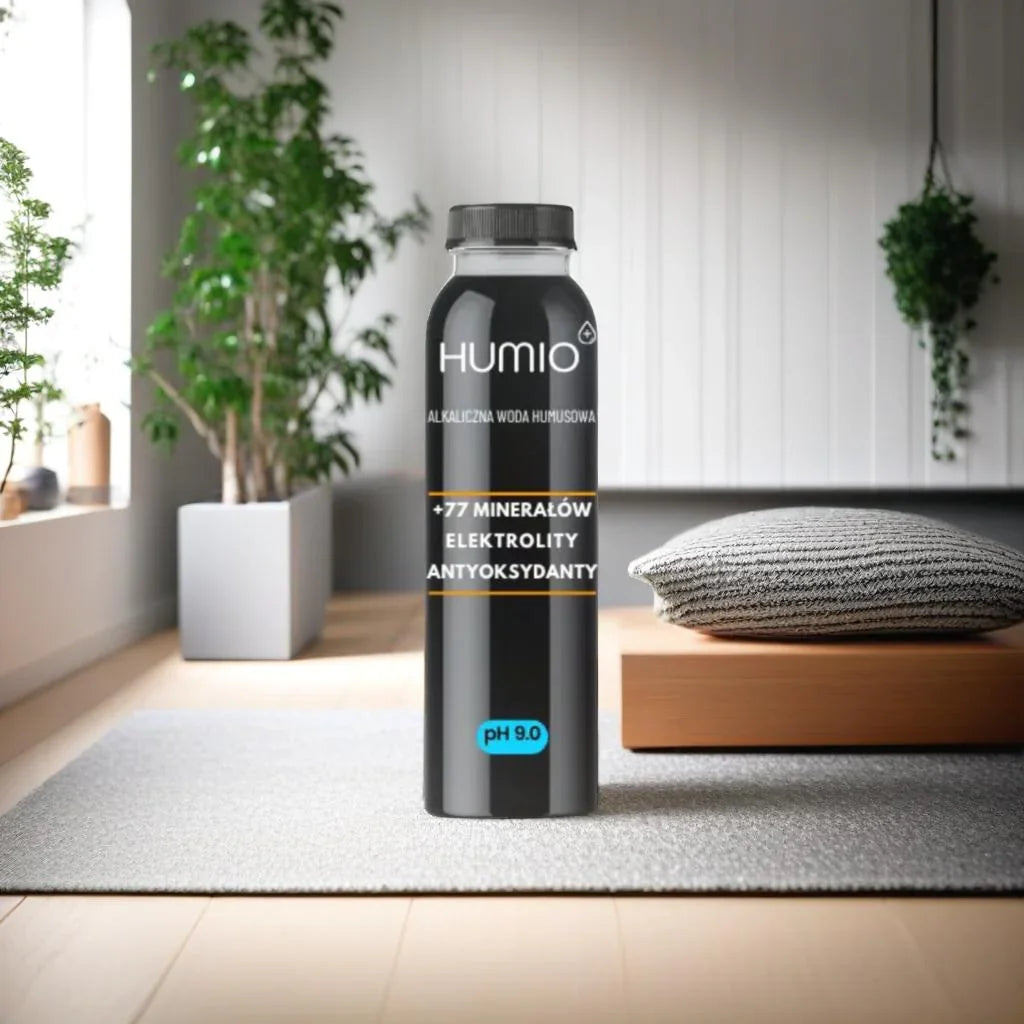 Butelka wody HUMIO na tle pokoju  – naturalna woda alkaliczna z kwasami humusowymi.